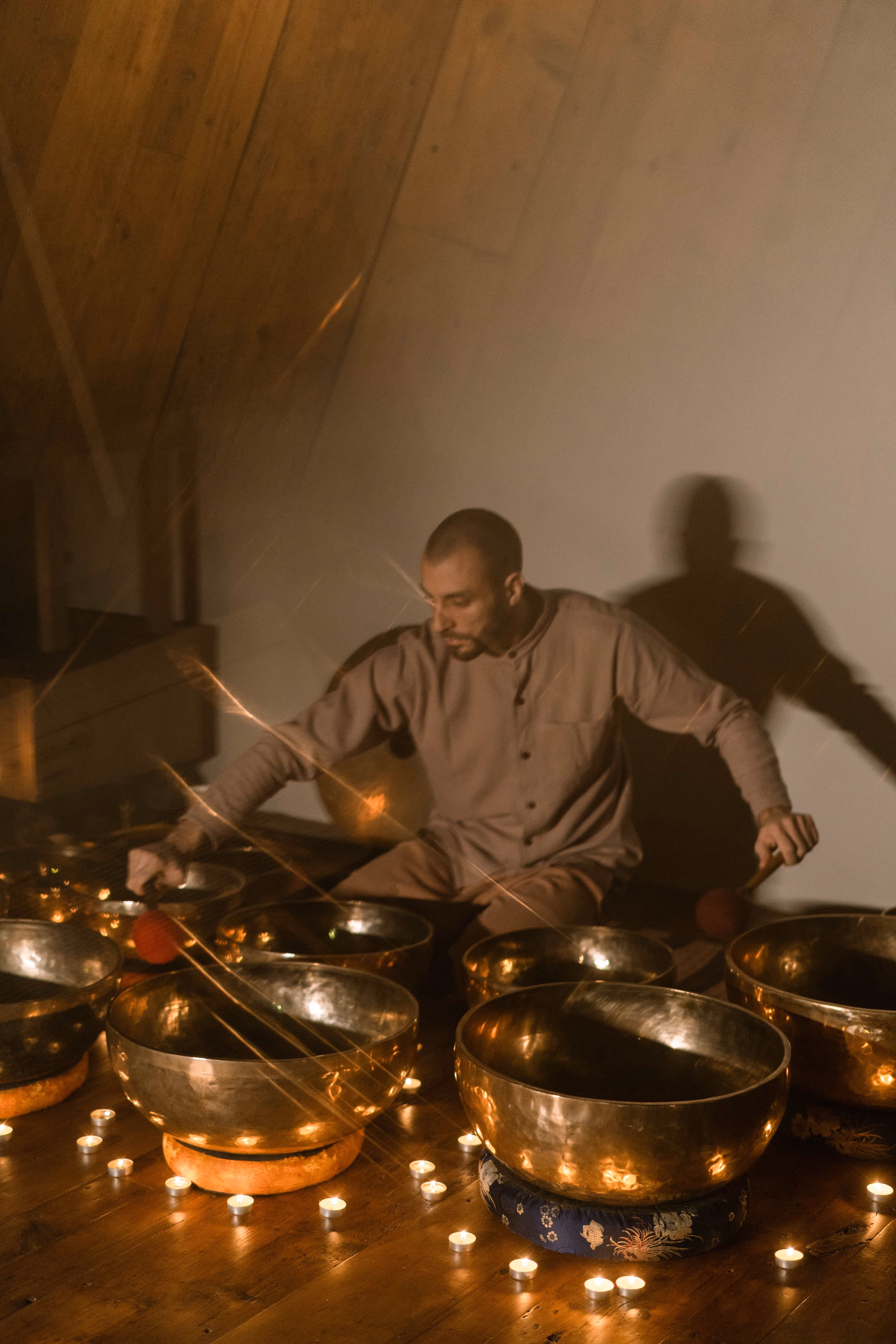 Long light trails curving around a brass singing bowl in a dark room.
